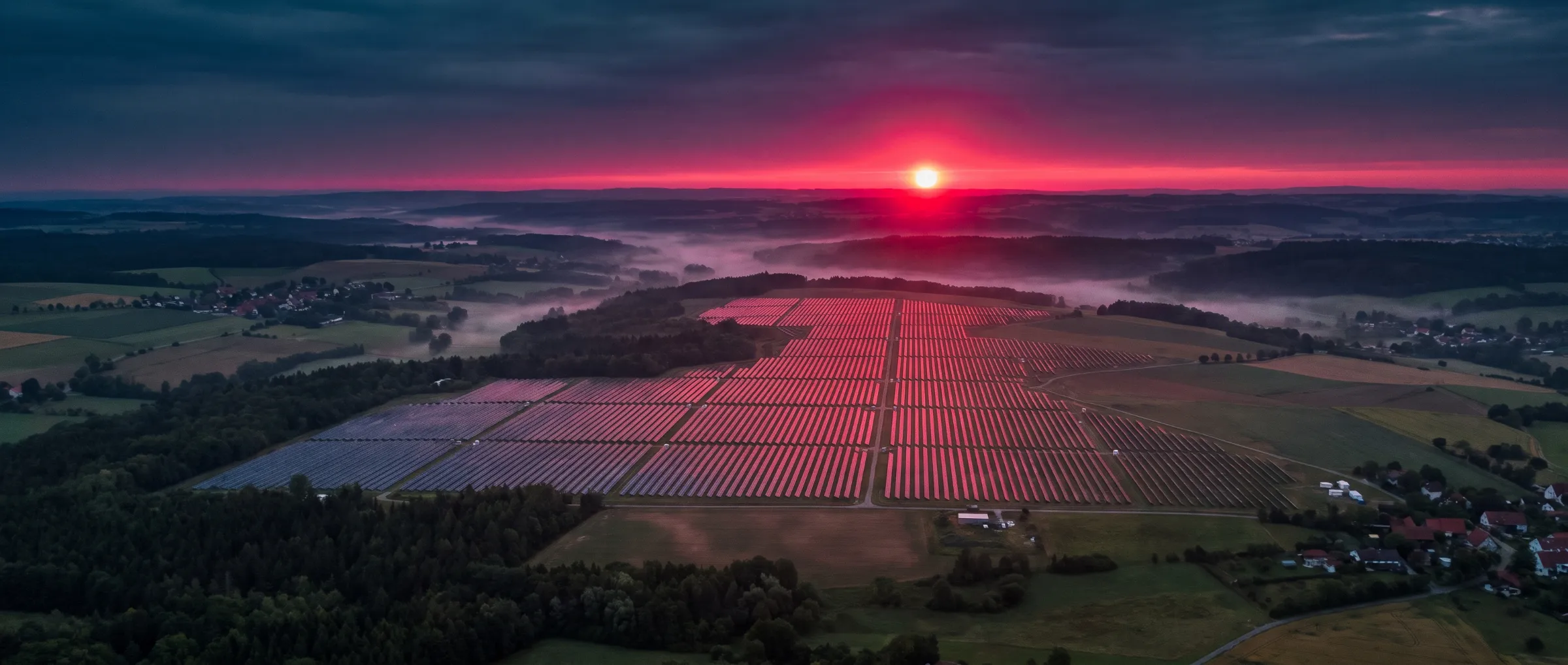 Solarpark auf einer Freifläche bei Sonnenaufgang aus der Luft